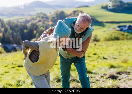 Donna anziana con dolore alla schiena durante la passeggiata autunnale, suo marito si prende cura di lei. Foto Stock