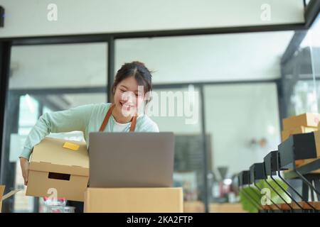 Un ritratto di una piccola startup, un proprietario di PMI, un imprenditore asiatico femminile che controlla gli ordini di organizzare il prodotto prima di imballare i prodotti in Foto Stock