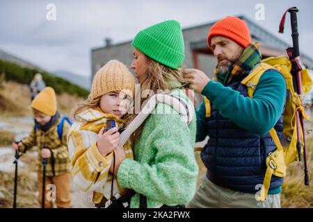 L'uomo aiuta sua moglie con la loro figlia stanca, dandola in portatore bambino, durante l'escursione autunnale in montagna. Foto Stock