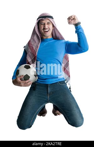 Uomo asiatico con keffiyeh che tiene la palla mentre celebra la vittoria con un'espressione eccitata isolato su sfondo bianco Foto Stock