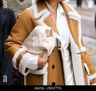 Milano, Italia - 21 settembre 2022: Donne alla moda che indossano un cappotto in pelle di pecora e una borsa bianca, vestito Street style Foto Stock