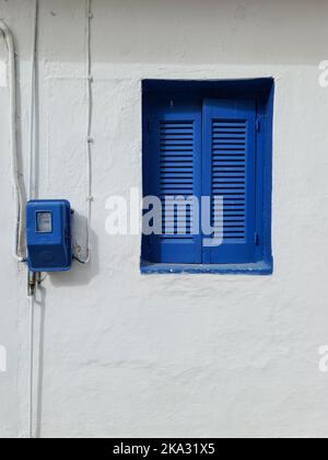 Una casa bianca con una luminosa finestra blu, verticale Foto Stock