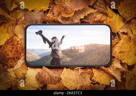 una giovane donna libera in montagna, sullo schermo di un telefono cellulare, che ha steso le braccia ai lati, denotando libertà e libertà di scelta. recreati Foto Stock