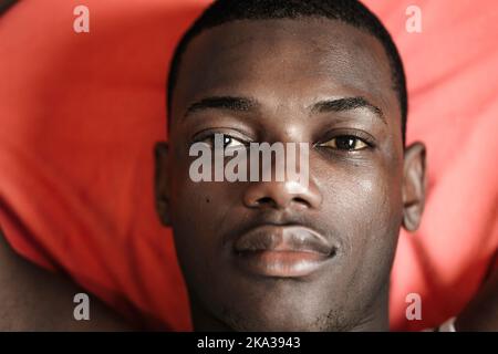 Primo piano uomo nero su coperta rossa Foto Stock