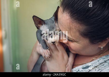 Donna che porta Sphynx gatto e baci Foto Stock