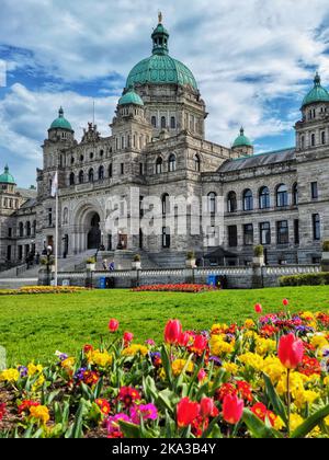 Uno scatto verticale del British Columbia Parliament Building e un giardino frontale con fiori di tulipano Foto Stock