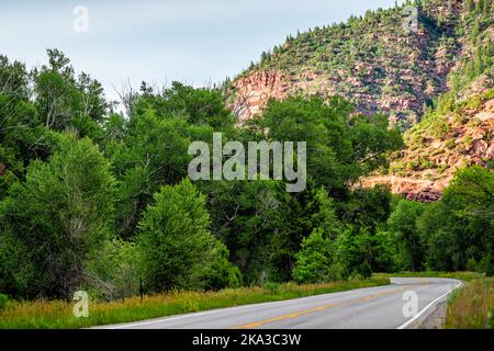 Montagne rocciose scogliera rossa dalla strada Highway 133 a Redstone, Colorado in estate con verdi alberi di Aspen alla luce del sole di sera Foto Stock