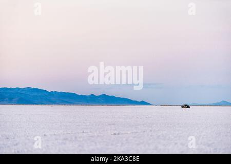 West Wendover, USA auto guida su Bonneville Salt Flats bianco vicino a Salt Lake City, Utah al confine del Nevada con colori pastello viola tramonto Foto Stock