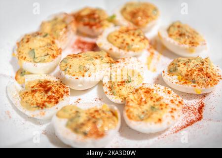 Macro primo piano di uova sode su piatto bianco con maionese, salsa paprika e prezzemolo Foto Stock