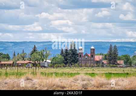 Autostrada 285 con paesaggio urbano di Conejos e la più antica chiesa del Colorado nella vecchia città d'epoca vicino ad Antonito con azienda vinicola vitigno campo di vigna Foto Stock