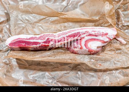 Macro closeup piatto top stendere di fresco barbecue crudo carne di maiale pancia pancetta grasso carne, nutritivo alimentare su carta bruna wrap Foto Stock