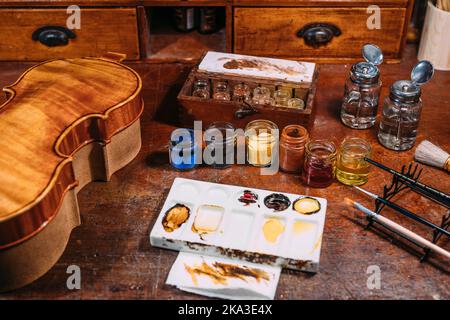 Dall'alto tavolo in legno con vernici e olio vicino al mix palette e violino in bottega di luziatore Foto Stock