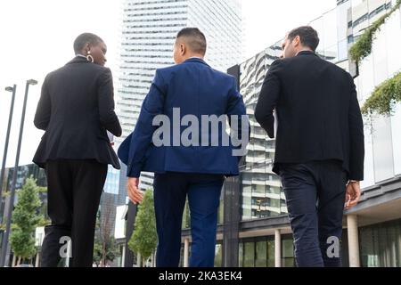 da sotto vista posteriore di uomini d'affari diversi e irriconoscibili in abiti formali che camminano sulla strada Foto Stock