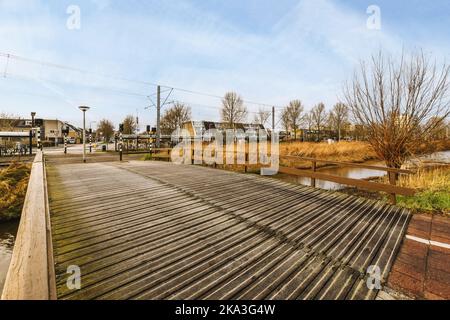 Tranquillo scenario di passerella in legno sul tranquillo fiume che scorre tra edifici residenziali Foto Stock