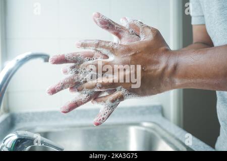 giovane uomo che lava le mani con acqua tiepida Foto Stock
