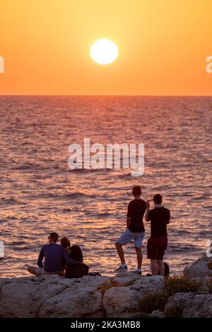 I turisti guardano il tramonto del sole sulla costa vicino a Paphos, Cipro. Foto Stock