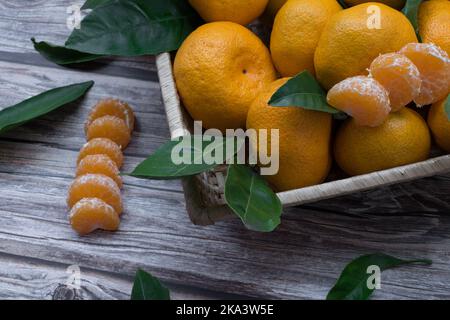 Primo piano di una scatola di tangerini e segmenti di tangerini su un tavolo di legno Foto Stock