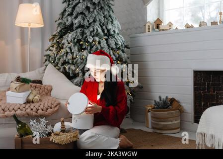 la ragazza apre il presente, la luce del presente risplende sulla persona. Un miracolo di Capodanno. Un regalo di Natale Foto Stock