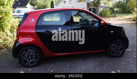 Itterbeck, Germania - Ott 16 2022 Vista laterale su un grazioso Smart per quattro EQ Electric Drive nei colori nero e rosso Foto Stock