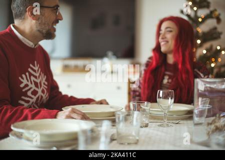 Uomo seduto al tavolo da pranzo un Natale con sua figlia adulta Foto Stock