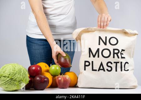 Una donna mette i prodotti in una borsa ecologica in tessuto senza più plastica. Il concetto di rifiuto della plastica Foto Stock