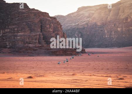 Il paesaggio del deserto del rum Wadi con una fila di 4WD veicoli parte dal punto di osservazione del tramonto in un tour organizzato al tramonto in Giordania Foto Stock