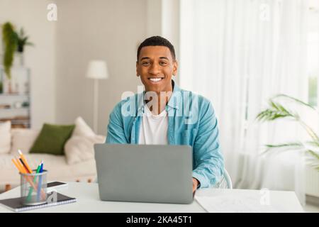 Sorridente giovane uomo d'affari o manager afroamericano usa il computer per studiare, lavorare Foto Stock