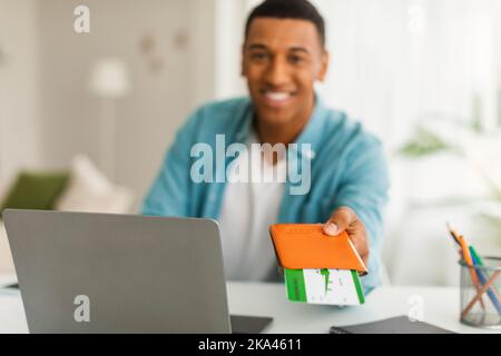 Felice uomo manager americano africano millenario con laptop che dà passaporto e biglietti aerei al cliente Foto Stock