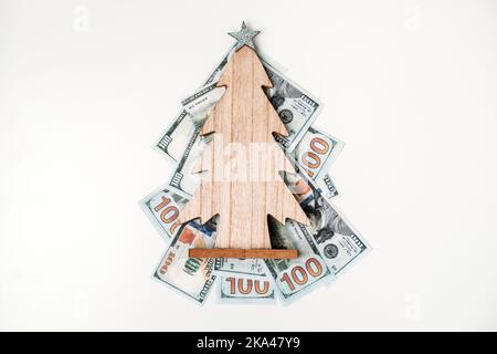Come spendere, il preventivo di Natale ed il concetto di risparmio. albero di Natale di legno sulla pila delle fatture del dollaro sulla tabella bianca Foto Stock