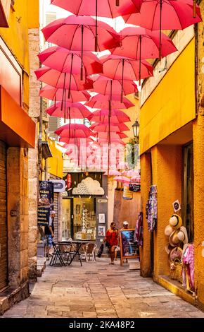 Grasse, Francia - 6 agosto 2022: Case storiche e strade strette decorate con ombrelloni rosa del centro storico della città profumeria Foto Stock