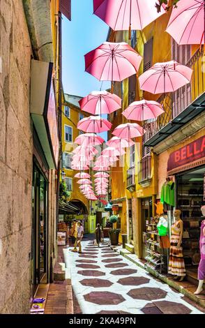 Grasse, Francia - 6 agosto 2022: Case storiche e strade strette decorate con ombrelloni rosa del centro storico della città profumeria Foto Stock