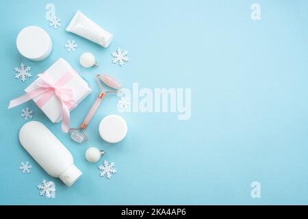 Cosmetici invernali con decorazioni natalizie su piatto blu. Foto Stock