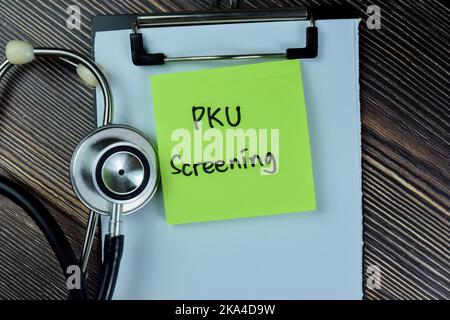 Concetto di screening PKU scrivere su note adesive con stetoscopio isolato su tavolo di legno. Foto Stock