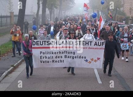 Lutherstadt Wittenberg, Germania. 31st Ott 2022. I partecipanti di una dimostrazione camminano lungo una strada con una bandiera e bandiere. Oltre mille persone hanno protestato contro la politica del governo federale in relazione alla guerra Ucraina e alla pandemia di Corona. Credit: Sebastian Willnow/dpa/Alamy Live News Foto Stock