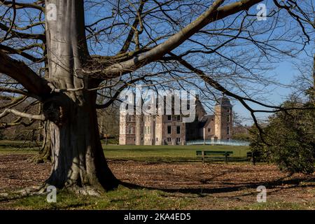 Inverno albero e rami aridi luminosi con facciata esterna in mattoni del castello di Ruurlo e ponte di accesso in vetro sullo sfondo Foto Stock
