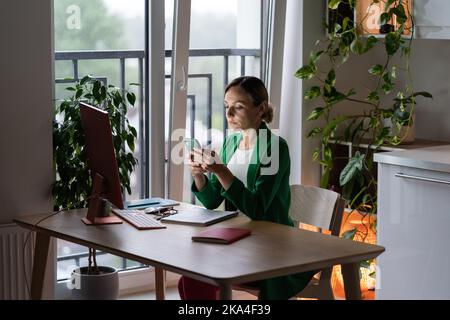 Occupato giovane donna esperto chiamata cliente partner sul cellulare, riposo lontano dal lavoro in un ambiente di lavoro accogliente. Foto Stock