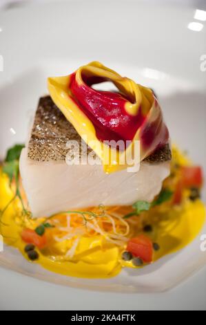 Pesce bianco servito con tortellone ripieno su crema gialla Foto Stock