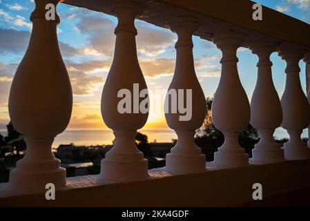 Alba dall'isola di Corfù che si affaccia sulle montagne della penisola balcanica della Grecia, Moraitika, Corfù, Grecia. In primo piano sono ringhiera balcone Foto Stock