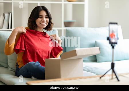 Bella giovane donna araba fare Unboxing Video per il suo Vlog di moda Foto Stock
