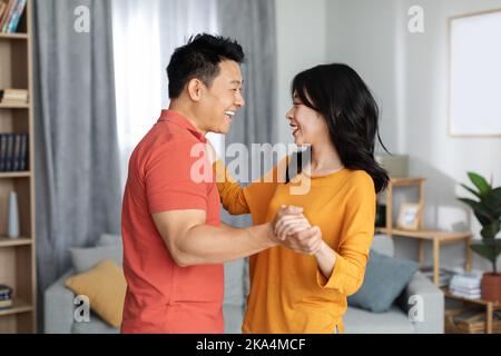 Romantica coppia asiatica godendo il tempo insieme a casa, ballando Foto Stock