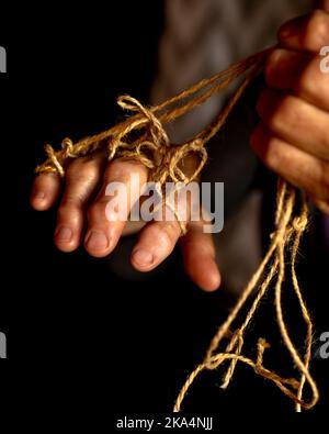 Mani di vecchia donna con malattia di poliartrite. Corde di tela sulle dita della signora anziana, marionette. Foto di alta qualità Foto Stock