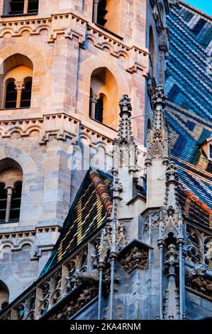 Guglie gotiche, torre romanica e colorato tetto piastrellato della Cattedrale di Santo Stefano a Vienna, Austria. Foto Stock