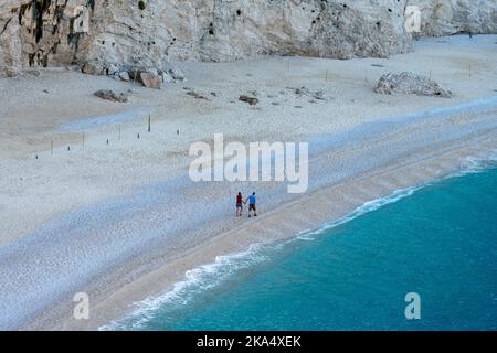 Una coppia in vacanza a piedi su una bellissima spiaggia di sabbia deserta. Foto Stock