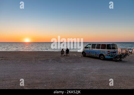 Isola di Lefkada. Grecia-10.17.2022. Un camper parcheggiato su una spiaggia con una coppia che si gode un bicchiere di vino e il tramonto. Foto Stock