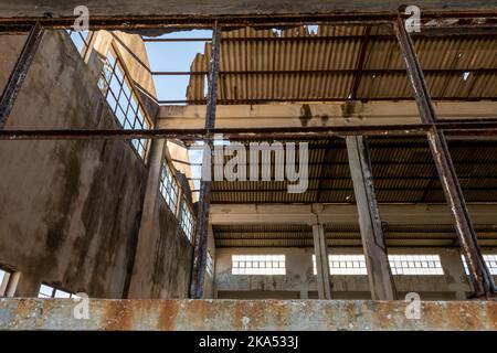 Vista interna di una fabbrica abbandonata che mostra la rottura del tetto in amianto. Foto Stock