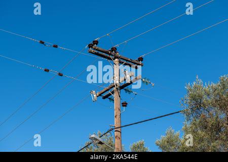 Cavo elettrico sospeso su pali di legno che portano la fornitura di energia elettrica alle aree rurali. Foto Stock