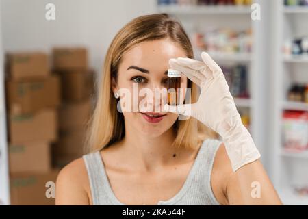 Il nutrizionista cosmetologo tiene l'olio della bottiglia del siero della faccia nel suo deposito degli additivi biologicamente attivi Foto Stock