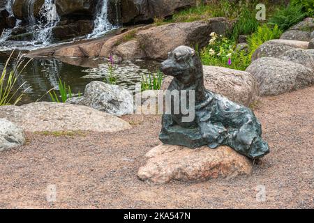 Finlandia, Kotka - 18 luglio 2022: Parco e lago di Sopokanlahti. Primo piano di una statua di sigillo in bronzo verdastro alla base della cascata Foto Stock