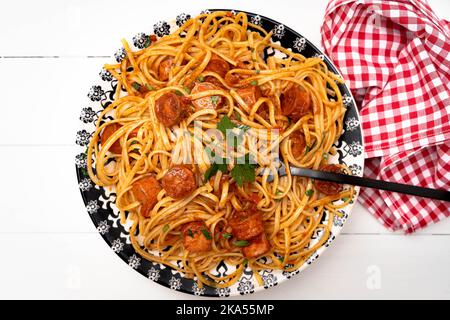 Sostanzioso piatto di pasta italiana con salsa di pomodoro e salsiccia con salsa su un rustico tavolo bianco. Vista dall'alto. Foto Stock