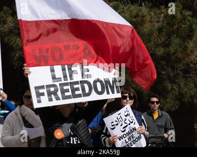 Reno, Nevada, Stati Uniti. 22nd Ott 2022. Un manifestante porta una bandiera iraniana e un cartello che dice: ''Donna, vita, libertà'' durante una marcia dimostrativa che condanna il governo iraniano e la morte di Masha Amini. A partire dall'Università del Nevada, centinaia di più di 2.000 iraniani americani di Reno hanno marciato attraverso il centro di Reno chiedendo la fine di ciò che hanno detto era il regime religioso oppressivo di IranÃ.Masha Amini è stata una figura centrale nelle manifestazioni. Amini è stato rapito dalla polizia morale iraniana e presumibilmente è stato assassinato mentre era in custodia del governo iraniano. Foto Stock